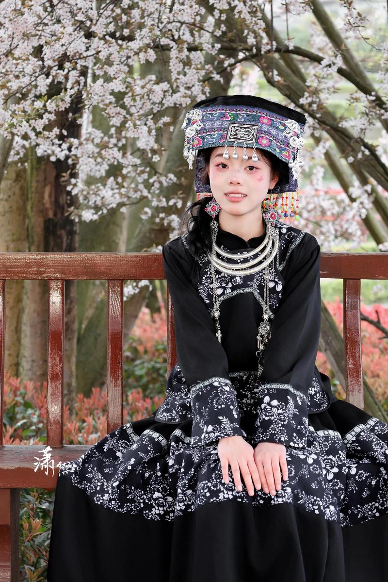 布依族服饰美美美.她身着精致的民族服饰端坐于此,黑色衣料上的